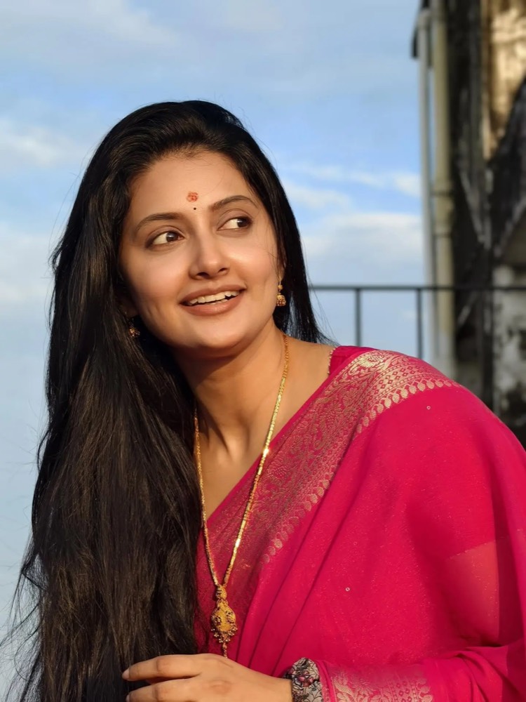 Debjani Modak in a magenta georgette saree with a gold pendant, on a rooftop at golden hour