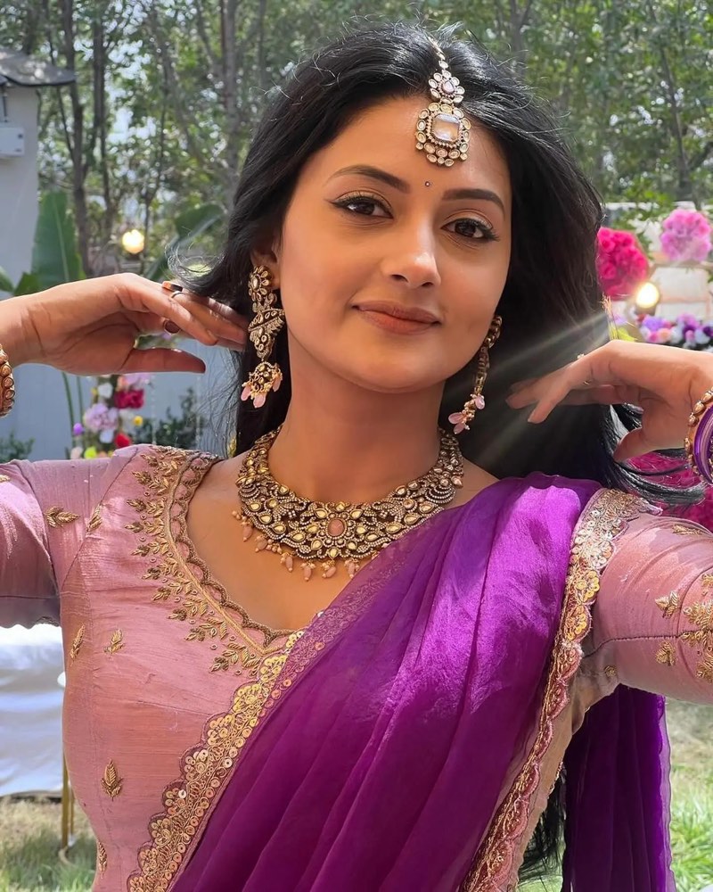 Debjani Modak in a purple saree with a maang tikka and a gold temple-jewellery necklace, outdoors