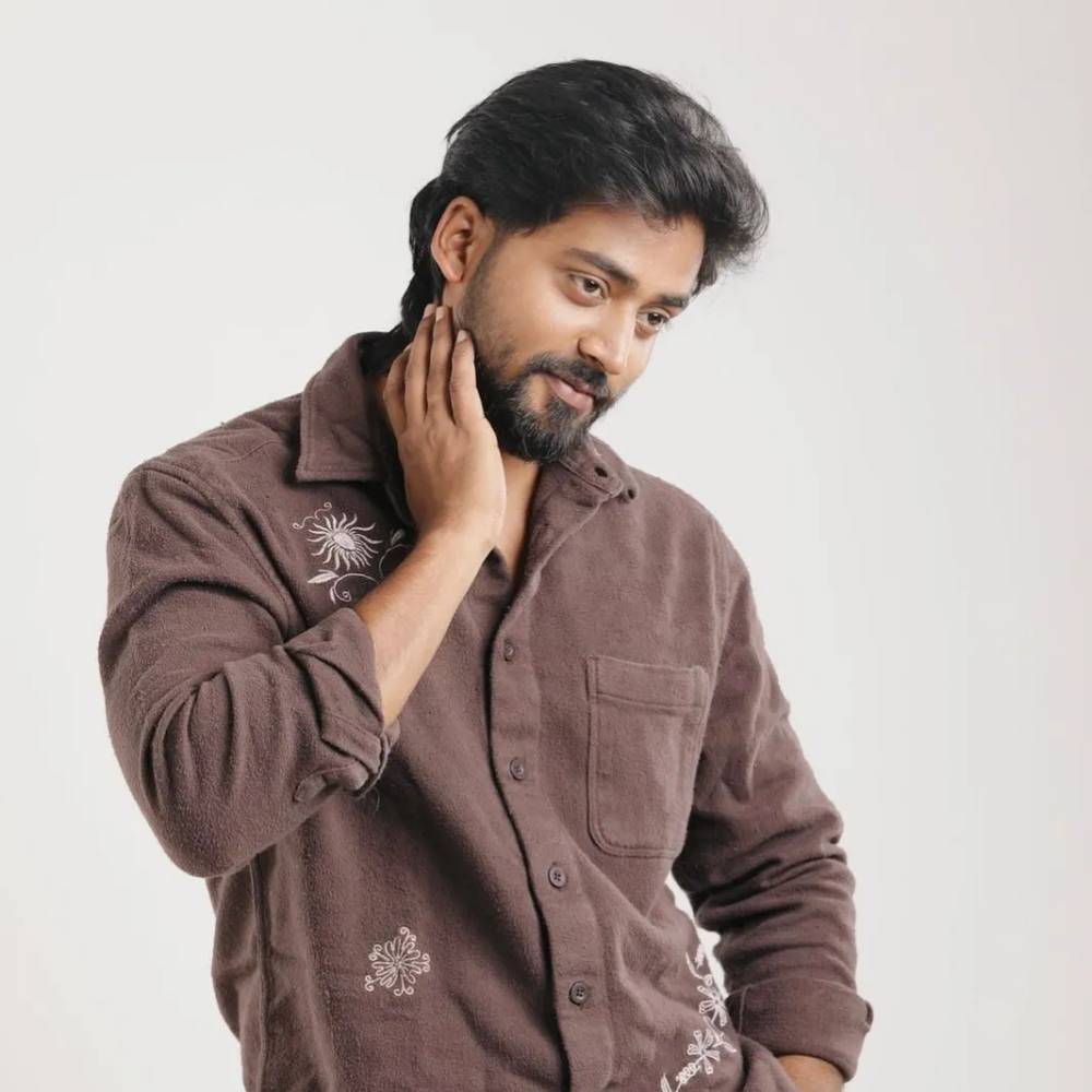 Mukesh Gowda in a brown embroidered overshirt against a plain white background