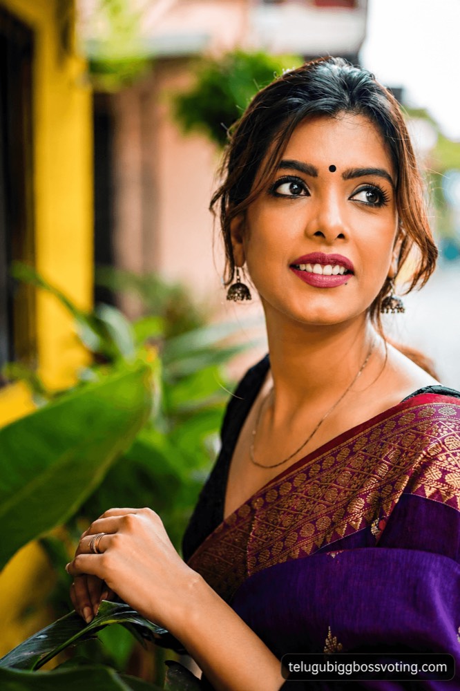 Illustrated portrait of Srishti Vyakaranam in a purple and gold saree with a bindi, looking away on a street