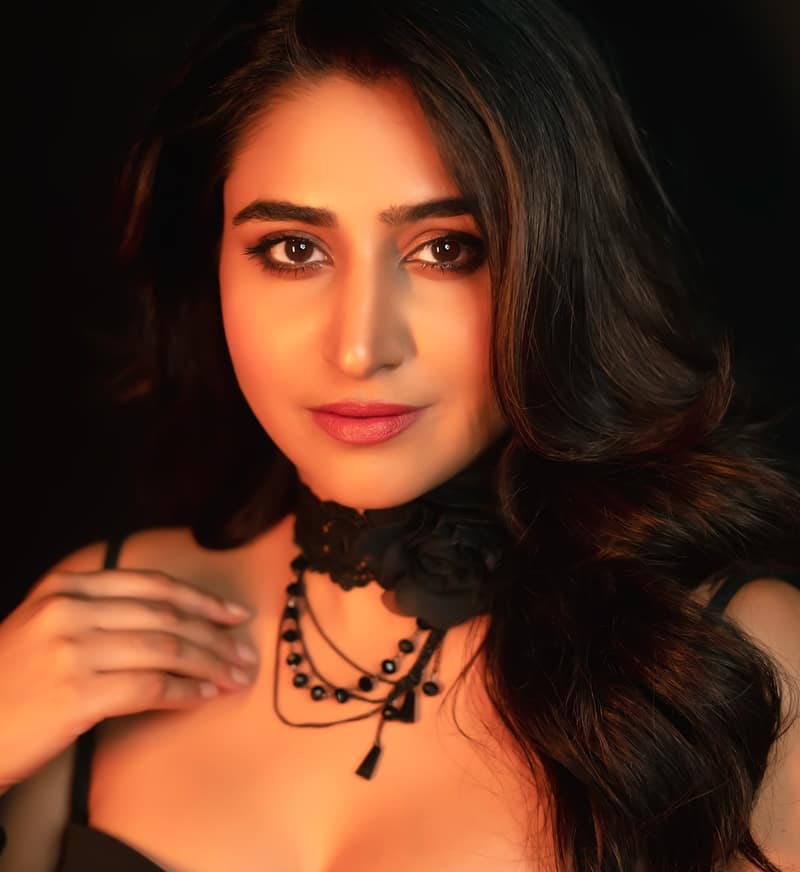Varshini Sounderajan in black against a dark background, one of her recent Instagram portraits